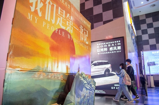 在武汉一家影城，观众从电影《我们是第一书记》海报旁走过（2021年12月3日摄）。新华社发（伍志尊摄）