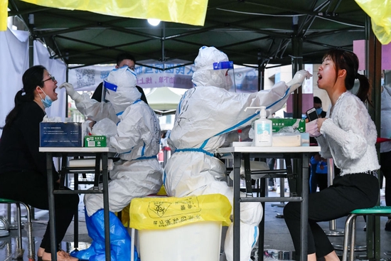 3月13日，在深圳罗湖区向西村核酸检测点，医务人员为居民进行核酸采样。新华社发（储焱摄）